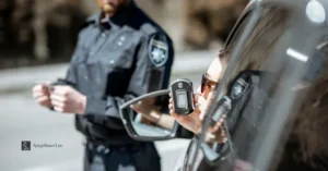 Police officer holds a breathalyzer device while a driver sits in a car during a Texas DWI traffic stop.